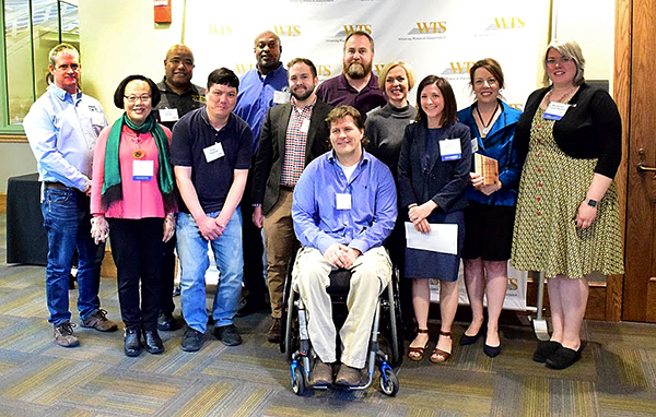 Picture of leage group of people, standing in two rows and smiling at the camera